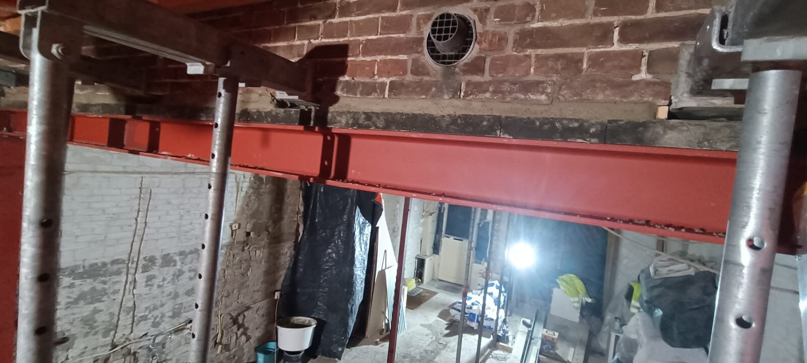 Red steel beams fitted under the brick back wall