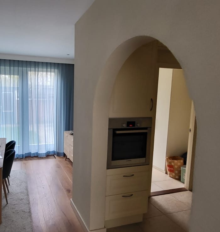 Before: a wall with an arched opening between the dining room and the kitchen