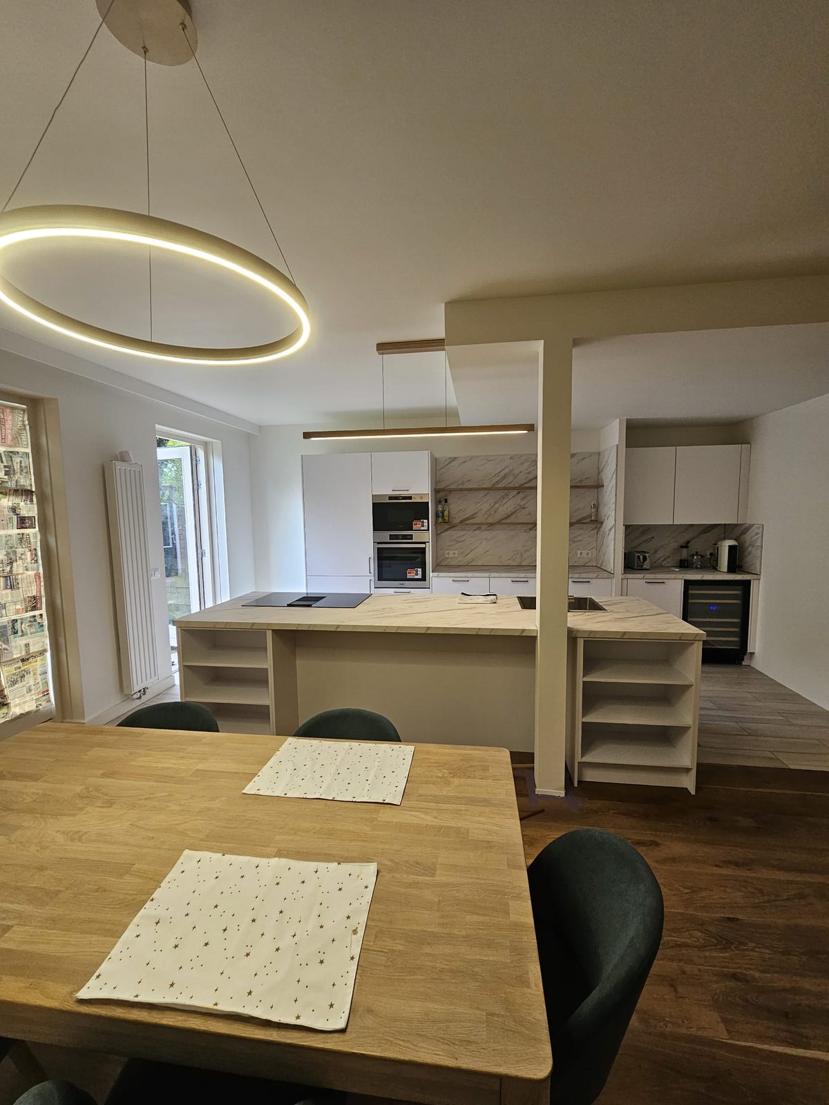 An open kitchen with an island next to the dining table, where a wall used to stand