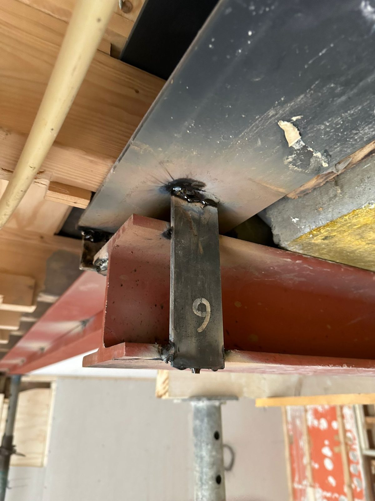 A bolted connection between two steel beams under a timber floor