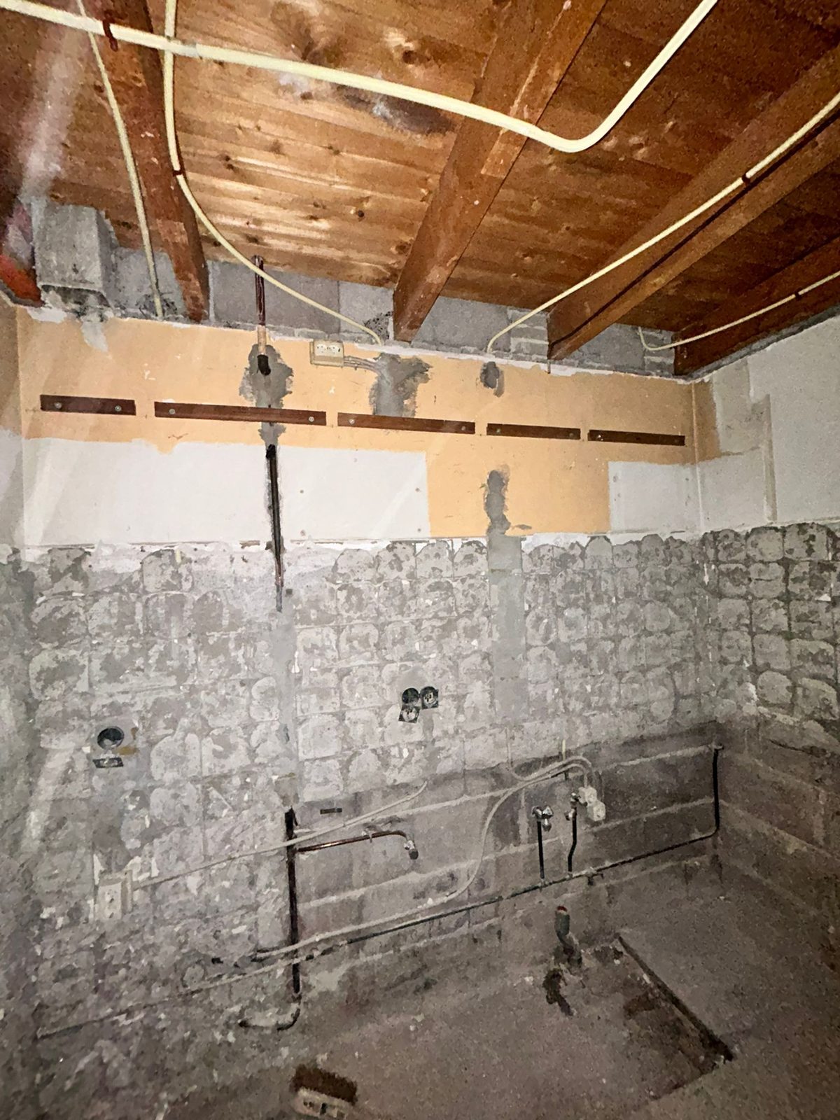 A stripped room with a timber ceiling and a beam across the wall