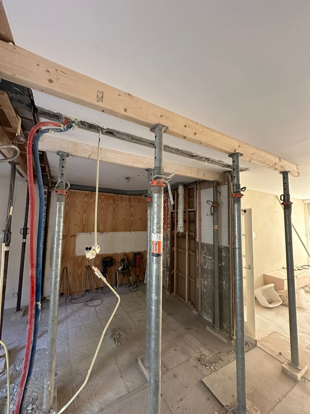 Temporary steel props under a timber beam in a stripped room