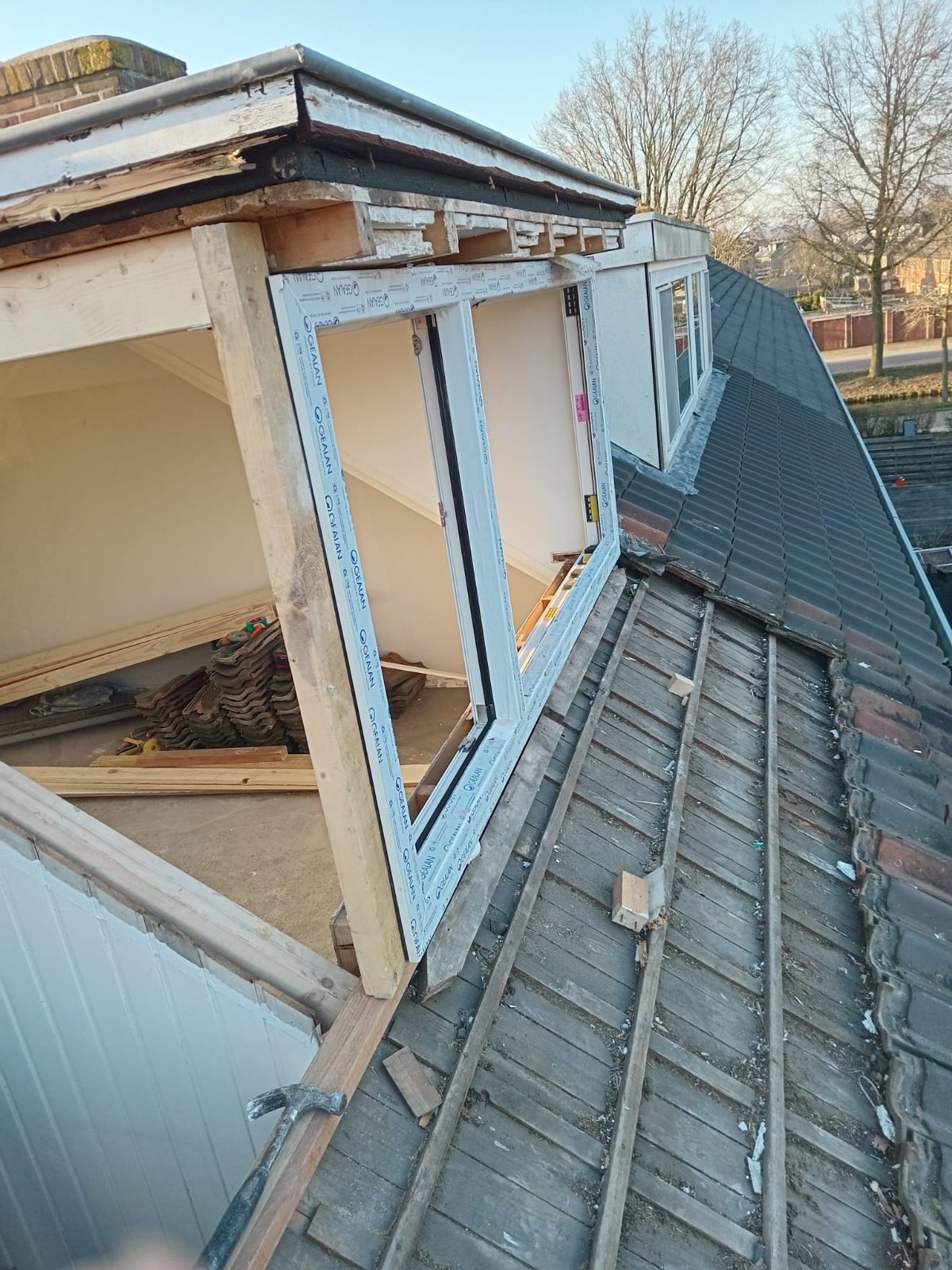 A dormer being built on the roof: the new cheek and window frame above the stripped roof battens
