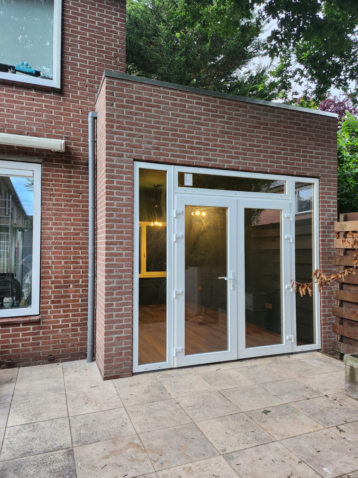 A brick side extension with glass double doors onto a tiled patio