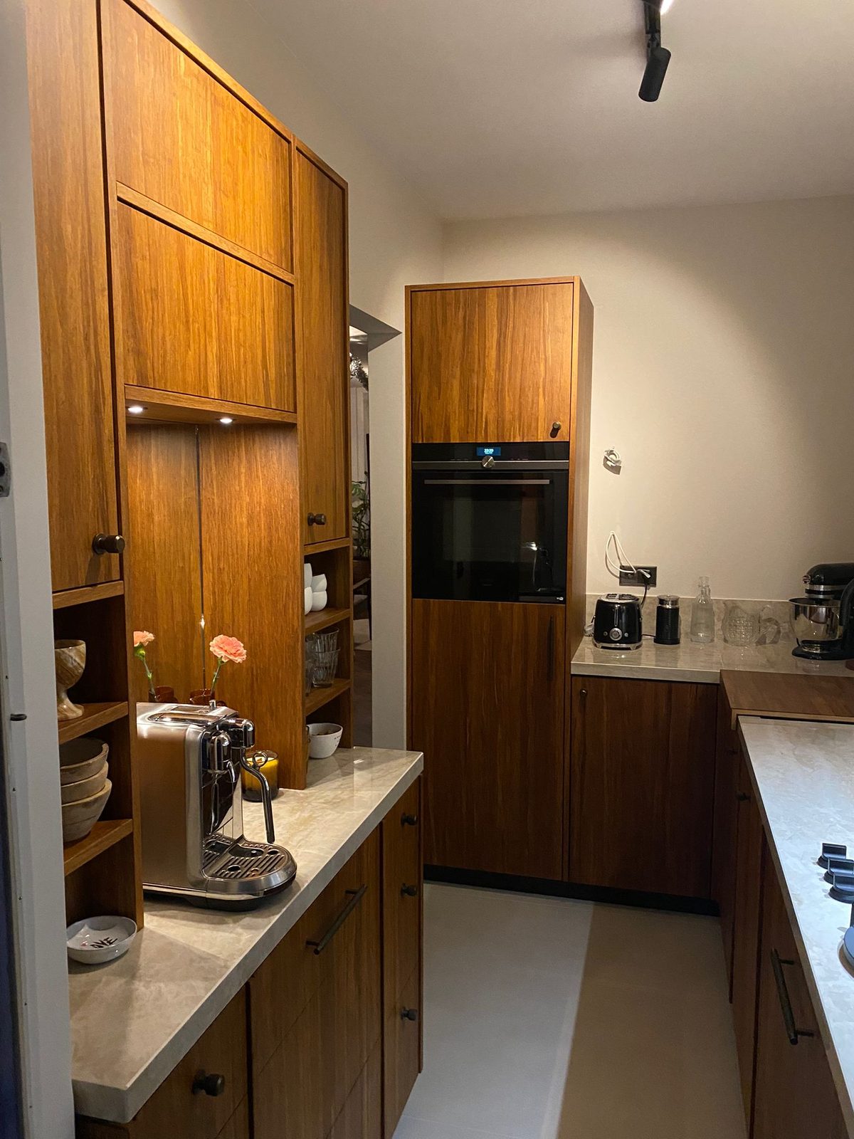 After: the same galley kitchen with walnut units and a light worktop