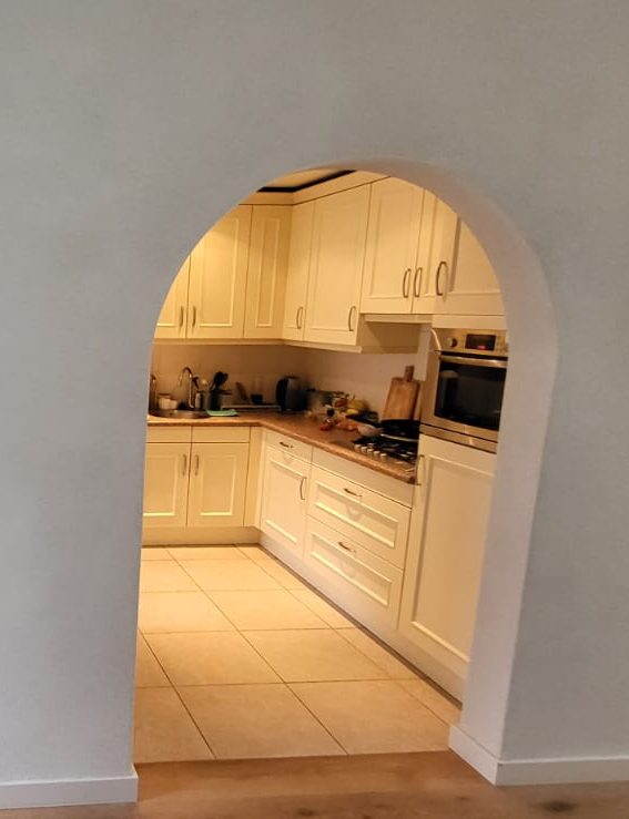 Before: the old kitchen behind an arched opening in the living room wall