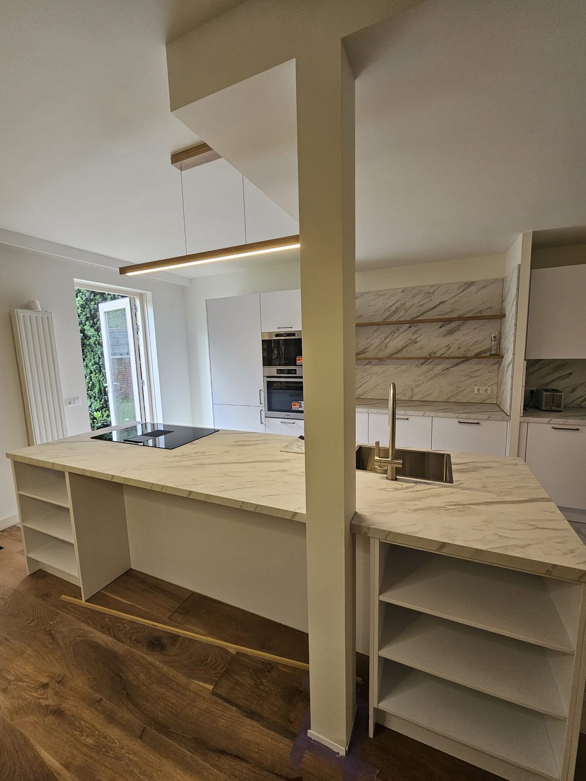 After: an open kitchen with an island and open shelves where the wall used to be