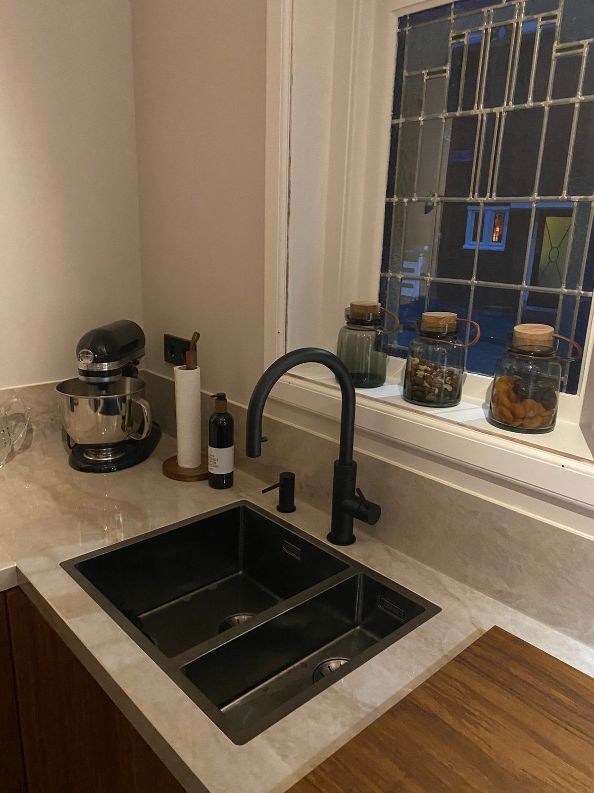 A black sink and tap under a stained-glass window