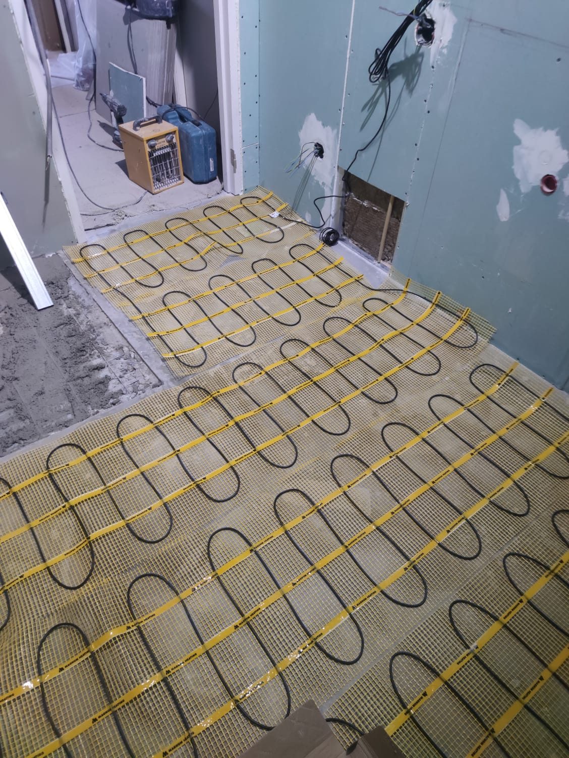 An electric heating mat on a bathroom floor before tiling