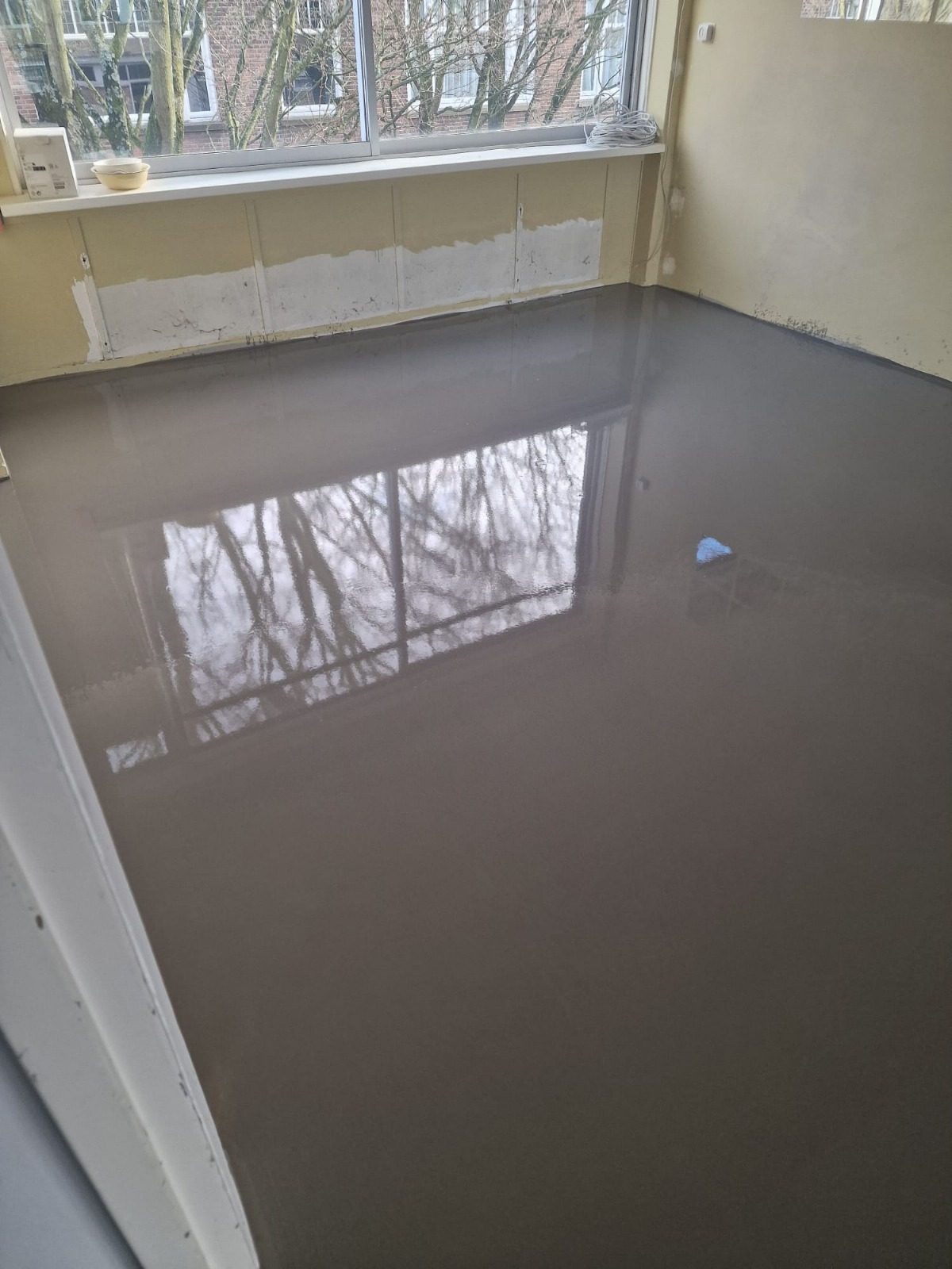 A room with fresh self-levelling compound reflecting the window