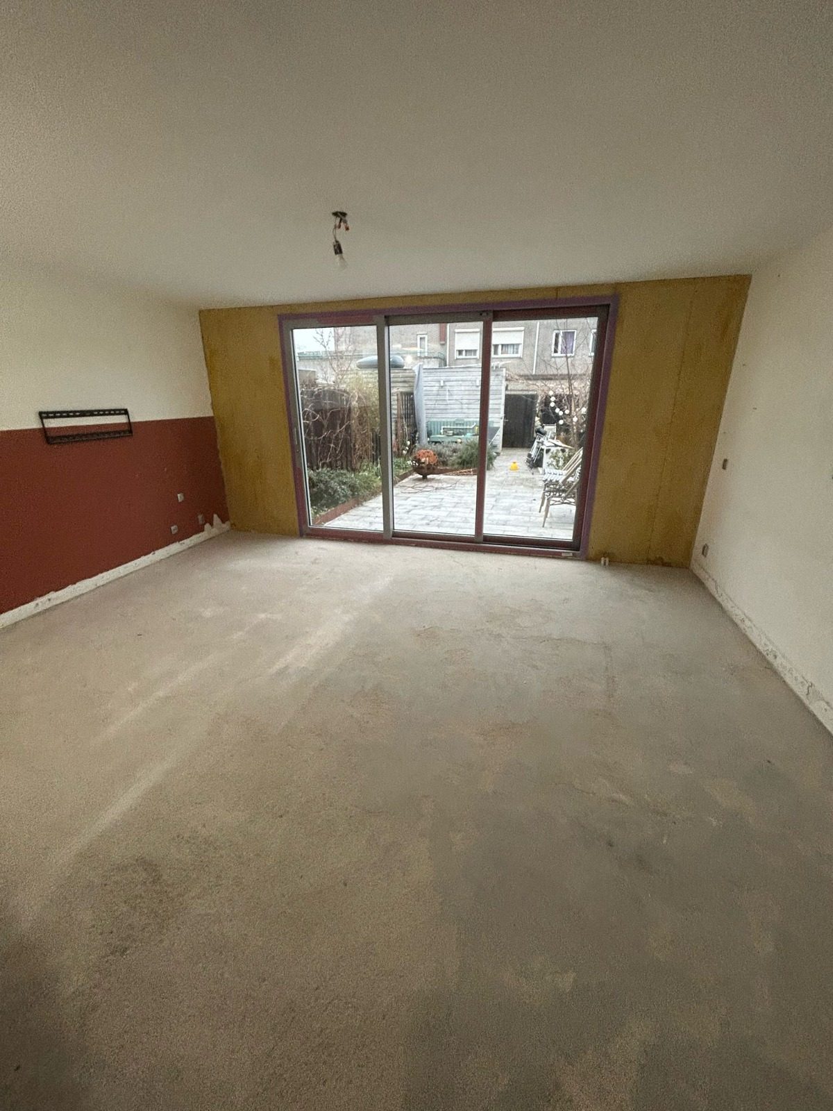 Before: a living room with a bare screed floor